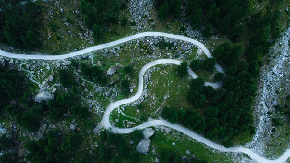 A winding path through lush forests and rocky landscapes in Bobbio Pellice, Italy.